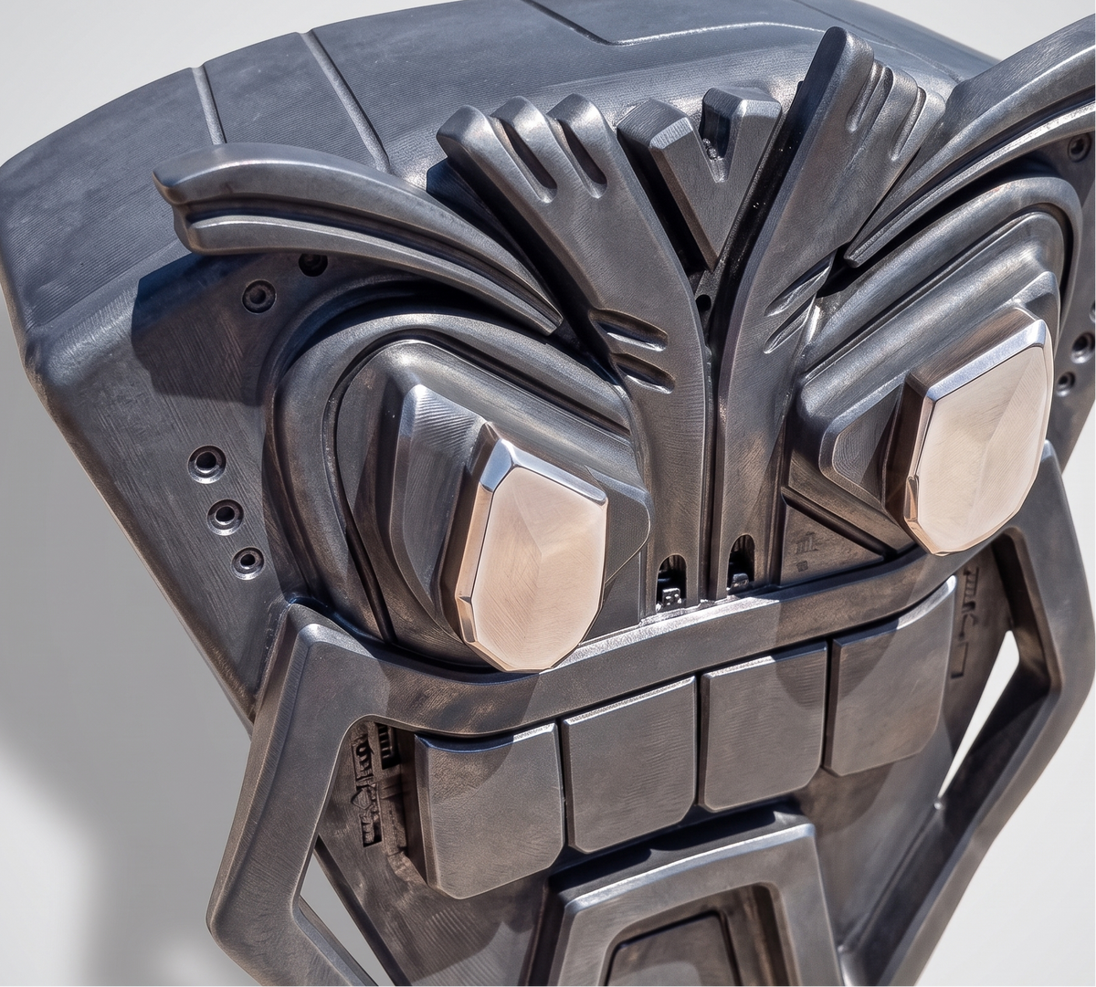 Metallic mask with a detailed design on a gray background